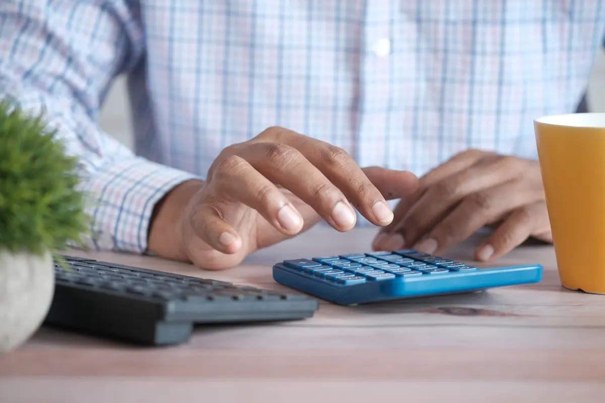 Persona calculando el crédito de formación bonificada de una empresa sobre la mesa de una oficina
