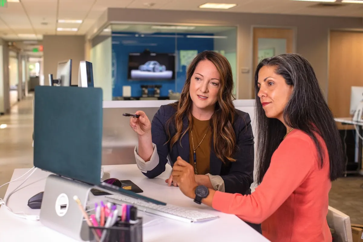Dos profesionales siguiendo una clase de inglés online para empresas desde su puesto de trabajo